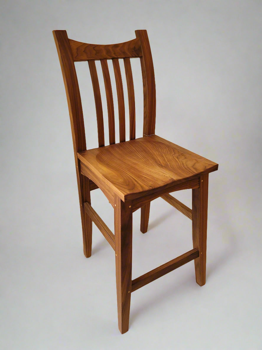 Wooden chair with slatted backrest in a room with tiled walls and floor.