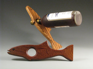 The Magic Salmon Wine Bottle Holder in assorted woods displays a fish design, supports sustainability at Hardwood Artisans
