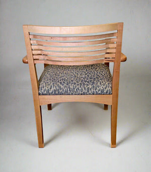 Wooden chair with patterned cushion against a plain wall