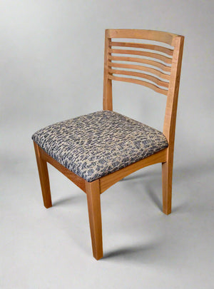 Wooden chair with a patterned cushion on a plain background