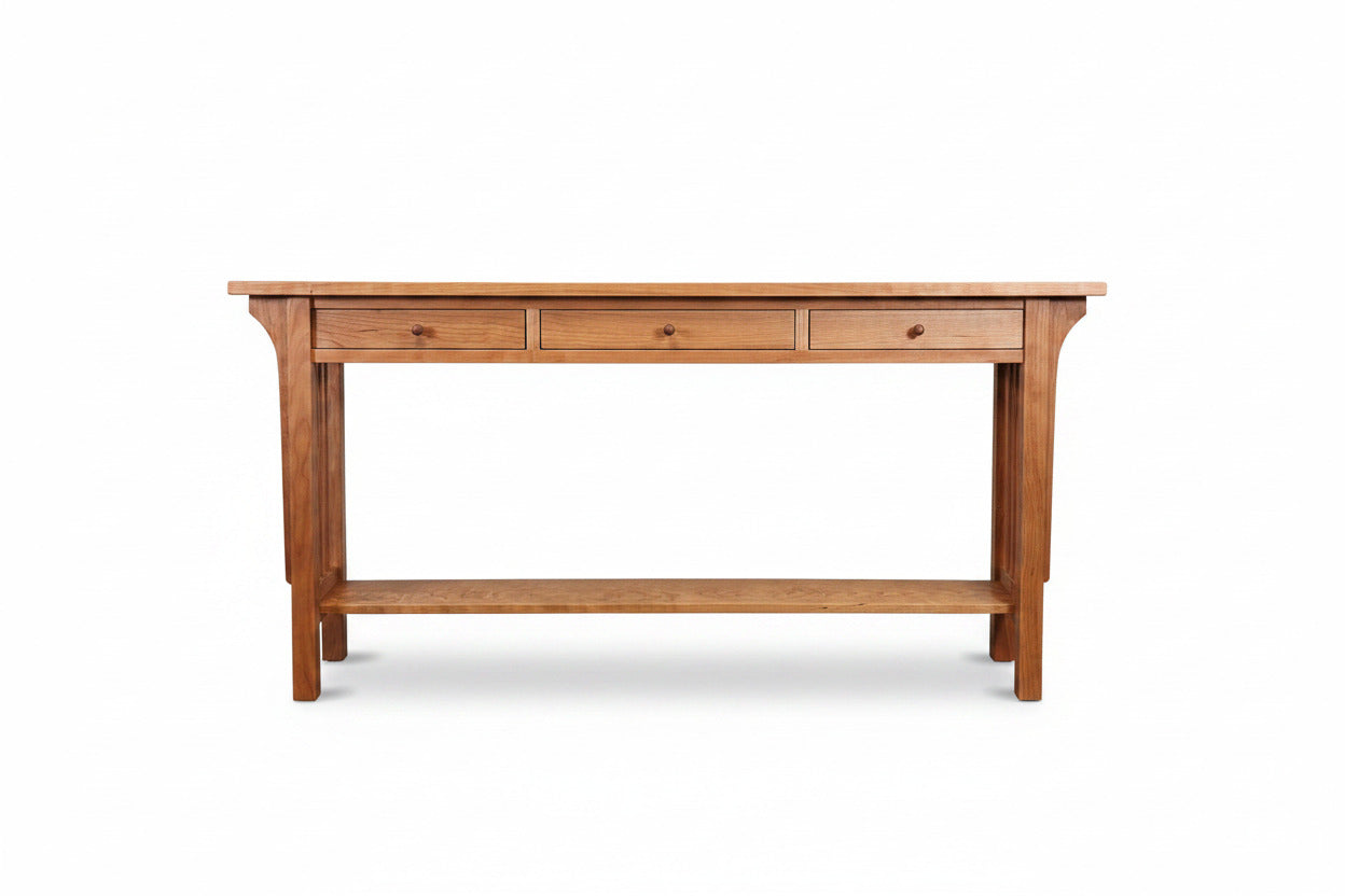 A wooden console table with three drawers, a lower shelf, and a warm medium-brown finish, set against a plain white wall and dark brown floor.